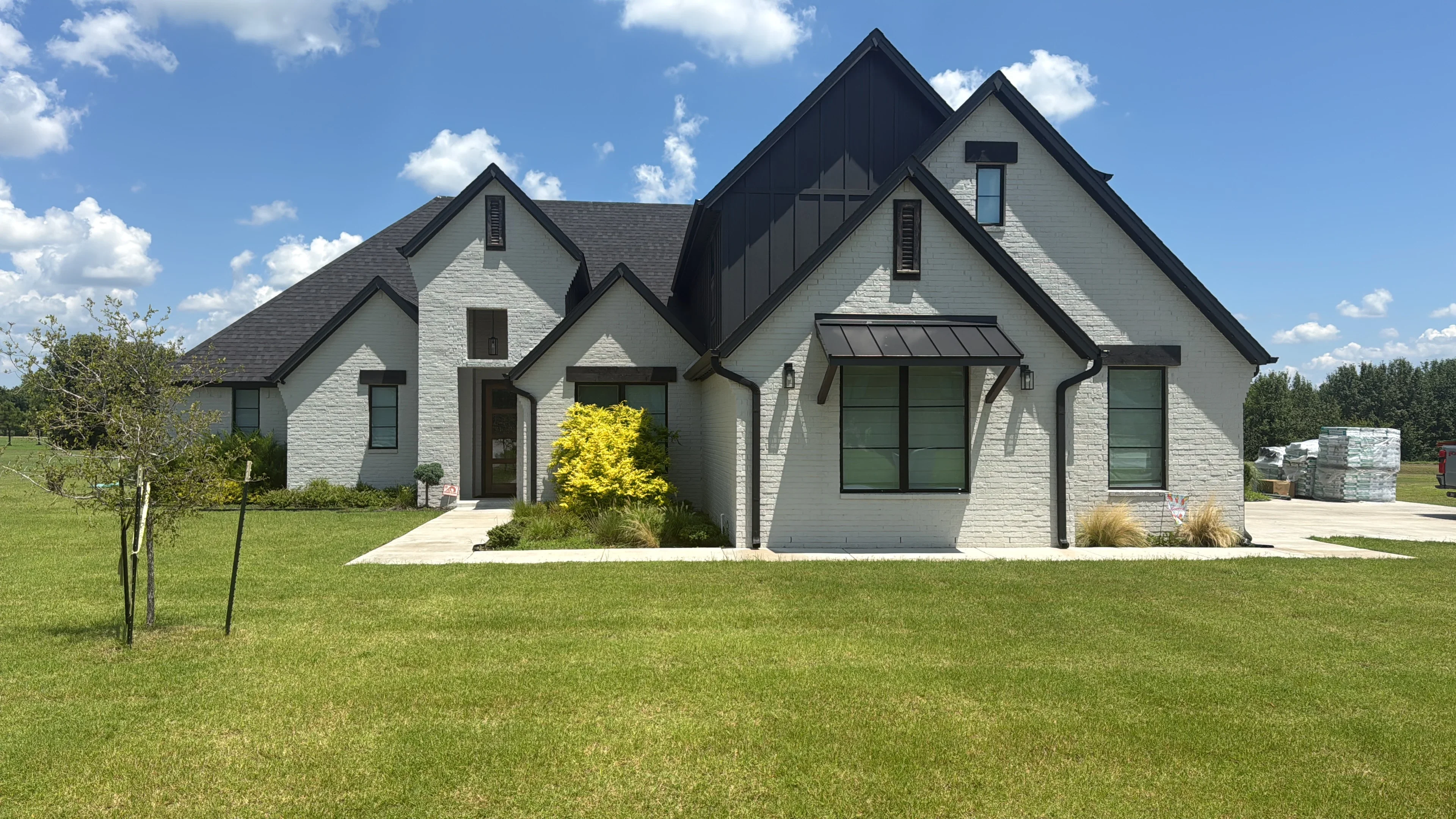 Dark architectural shingle roof on white brick farmhouse with multiple gables and dormers