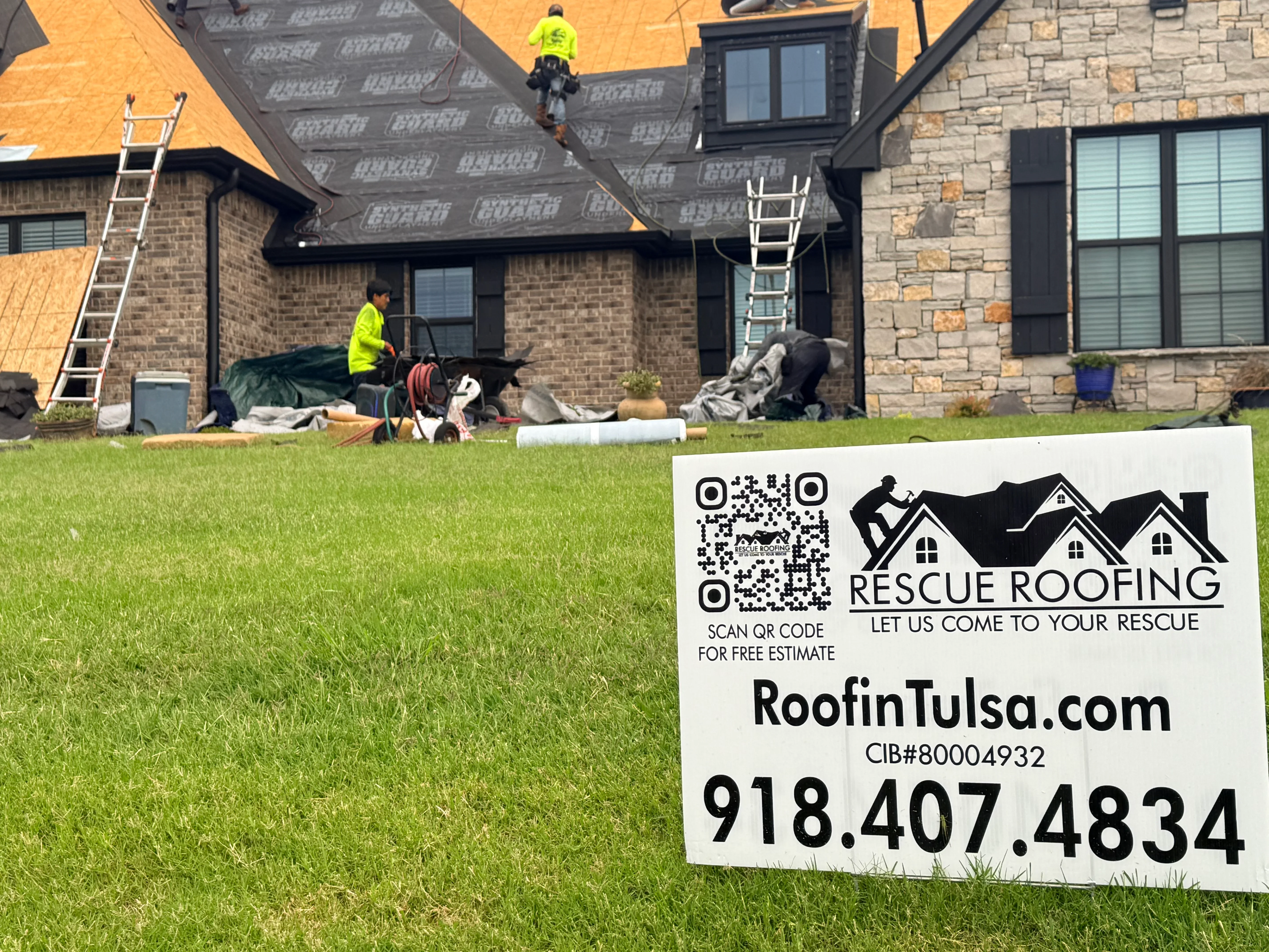 Roofers installing architectural shingles on multi-story brick home with dormers and yellow underlayment visible