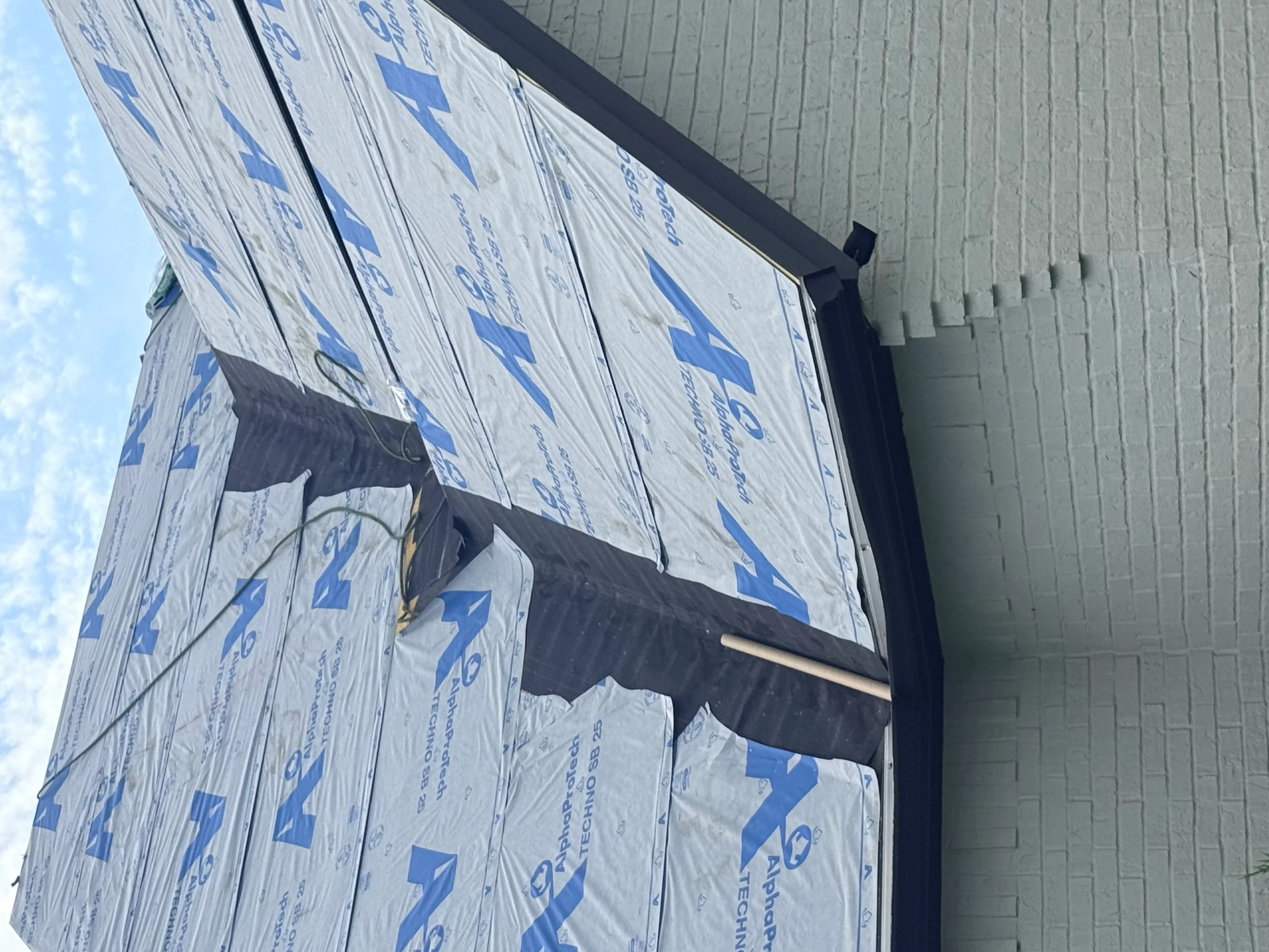 Roof sheathing with blue weather barrier membrane and black drip edge trim installation