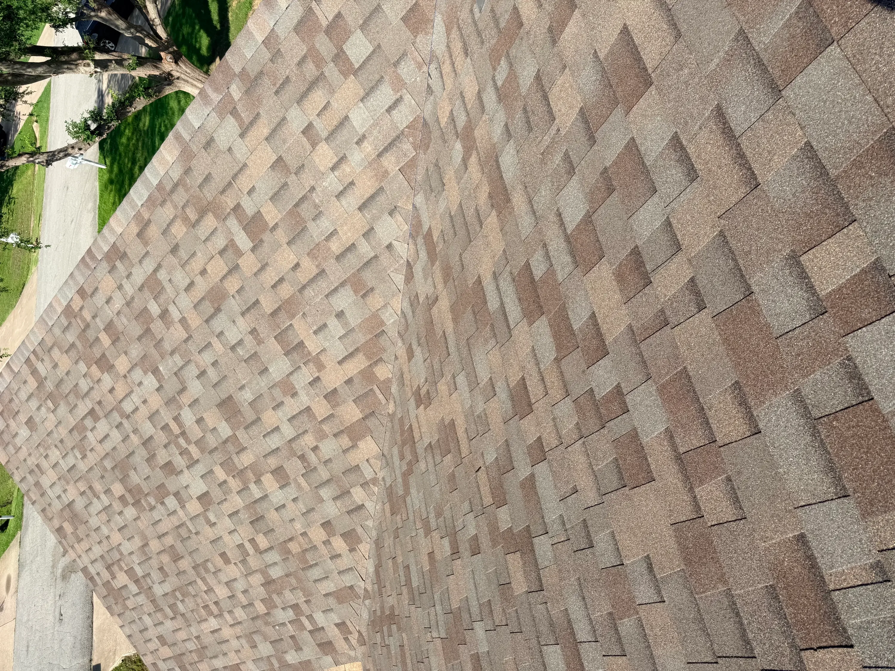 Newly installed architectural shingles in gray and brown tones with staggered pattern