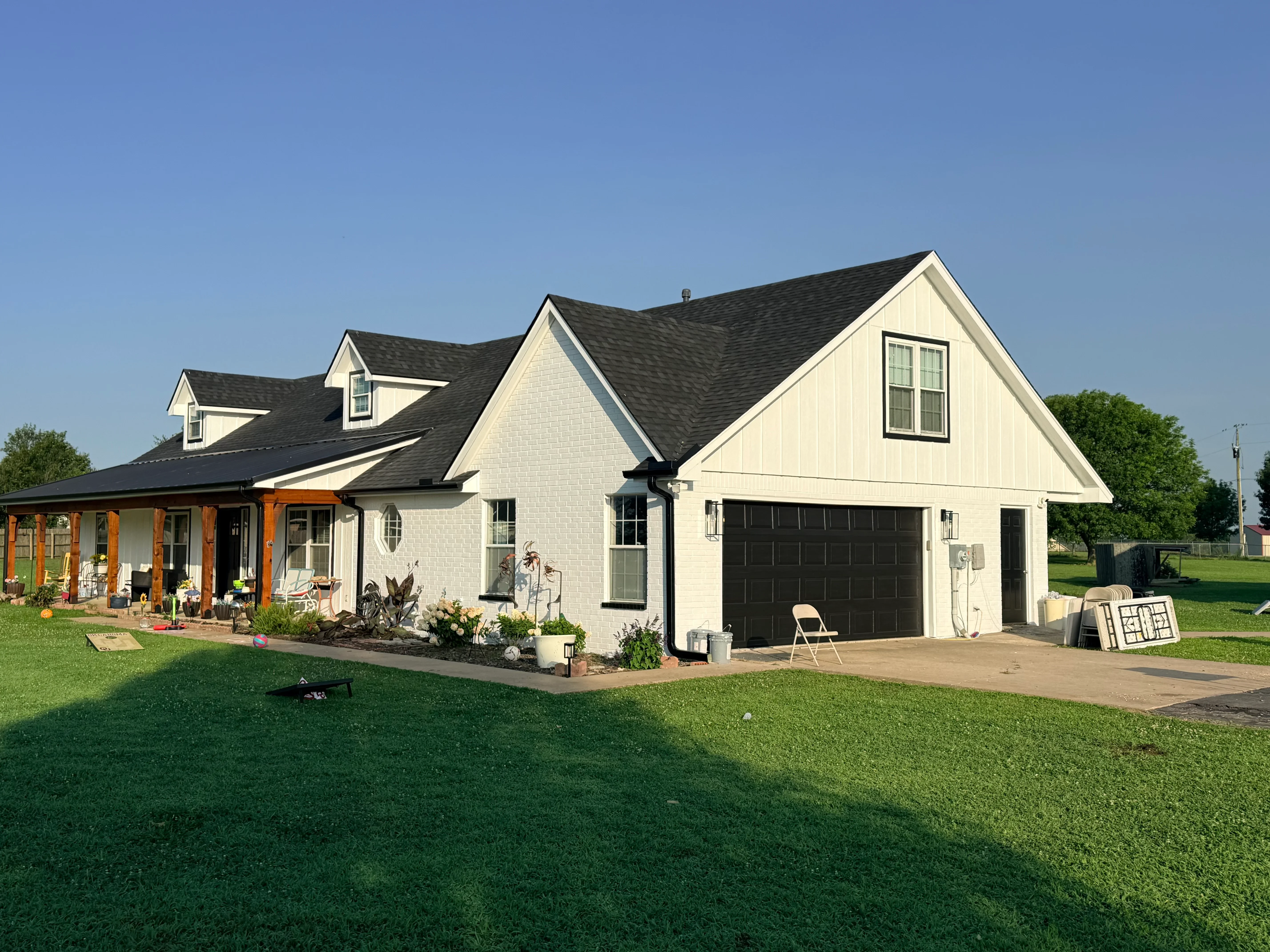 Charcoal gray architectural shingle roof on white farmhouse with multiple gables and dormers