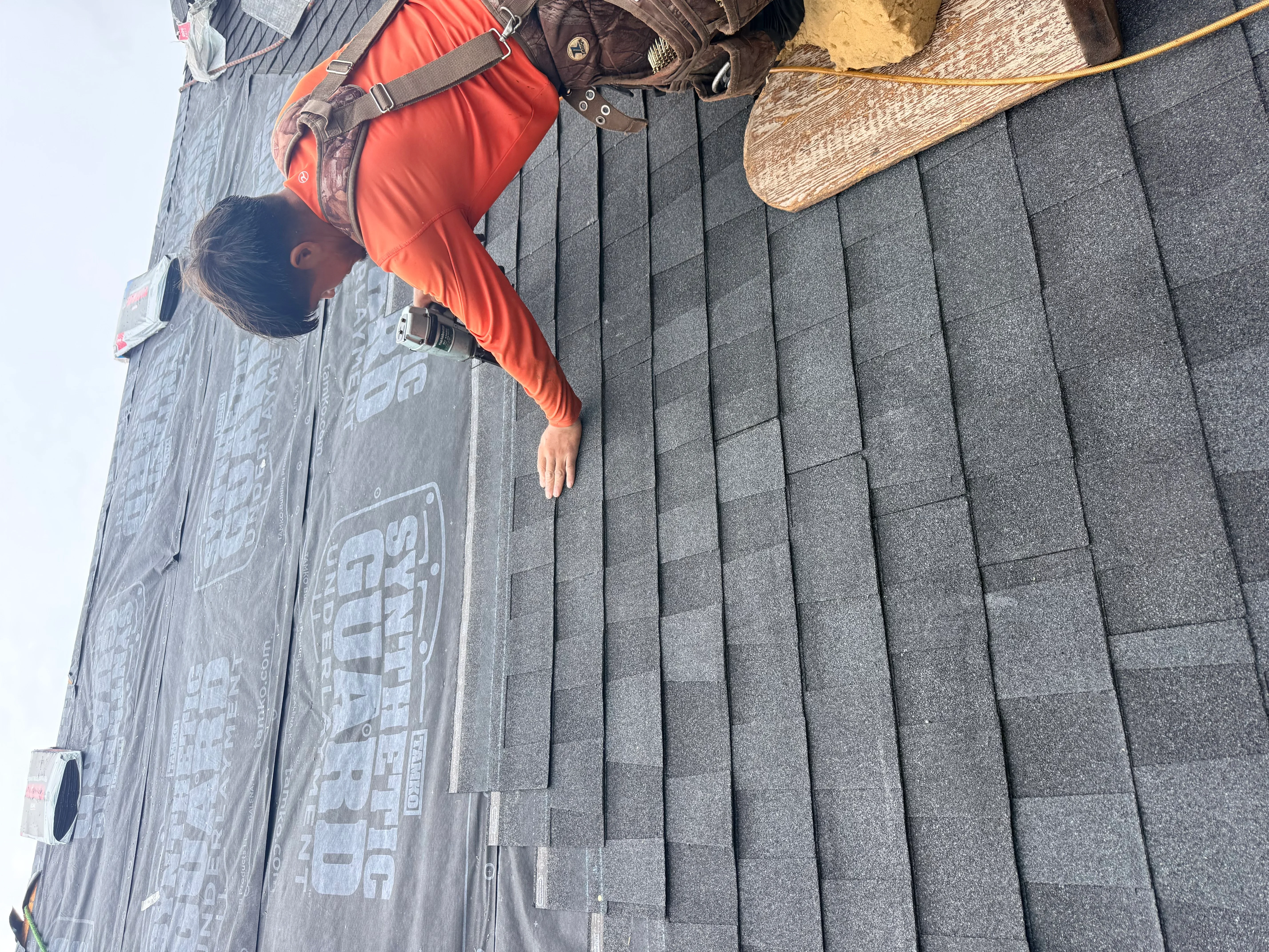 Charcoal gray architectural shingles installed in rows on pitched roof