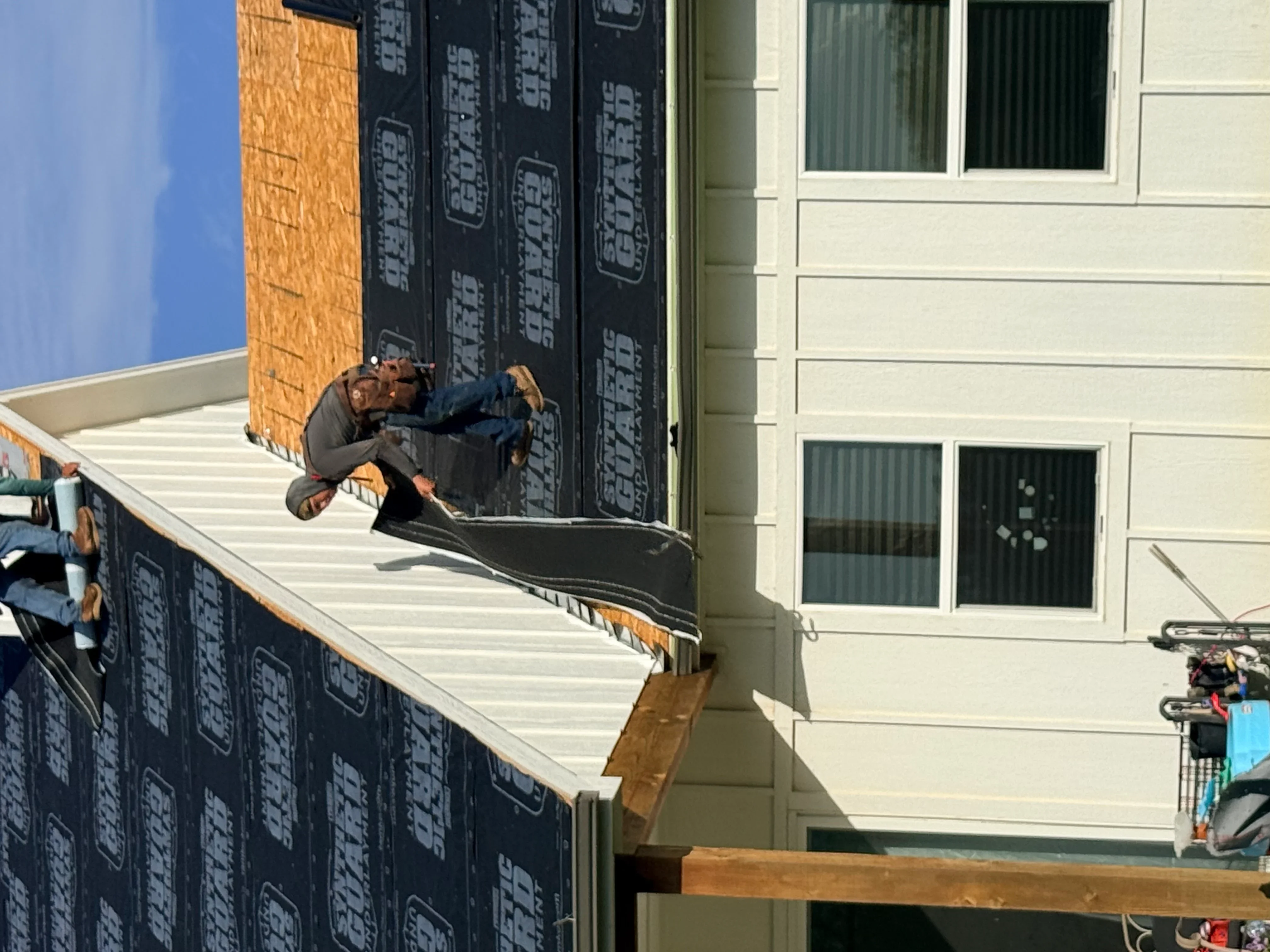Roofer installing underlayment and metal flashing on residential roof framing