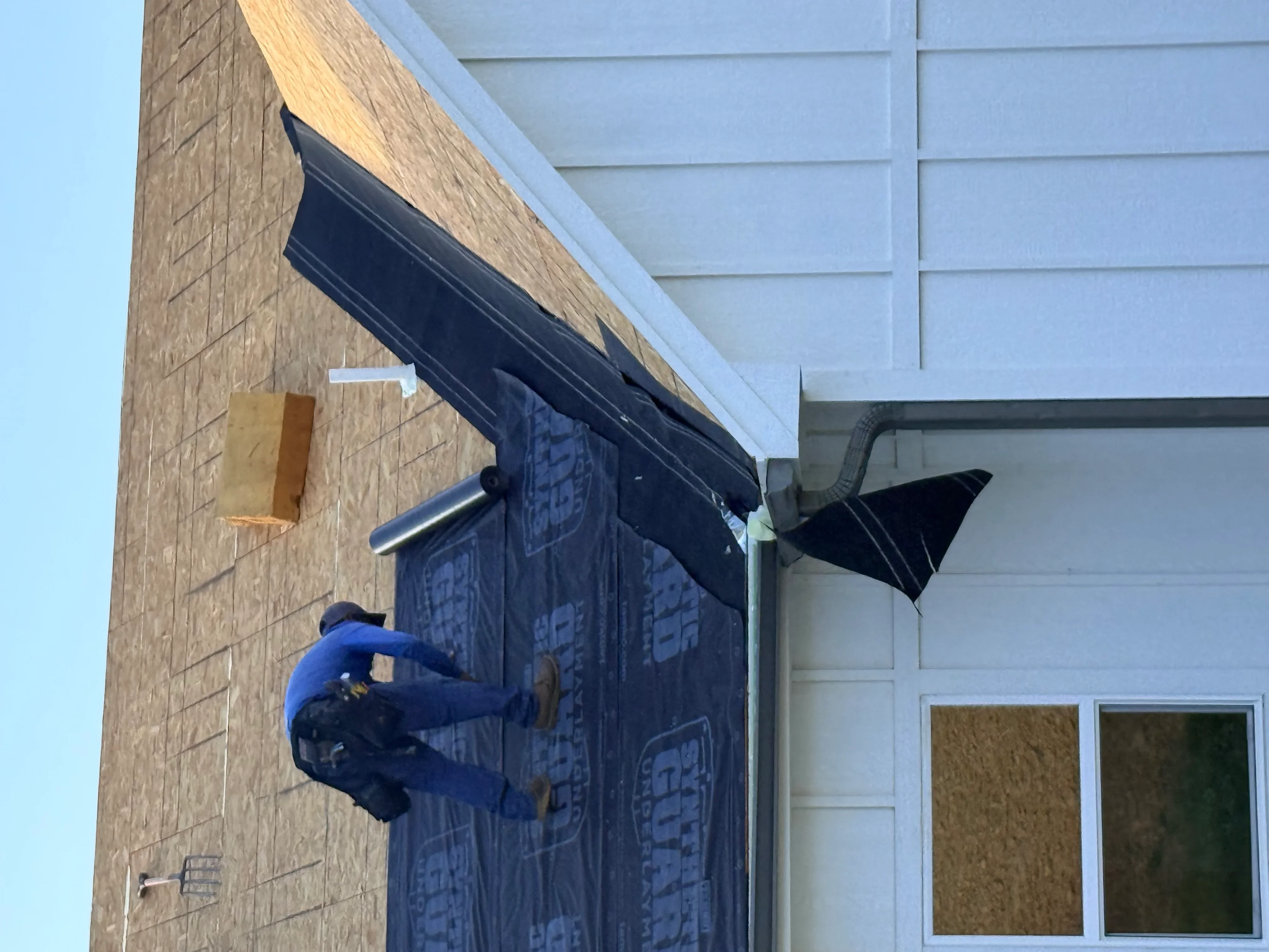 Black metal awning with white trim installed over brick entryway with gutter system