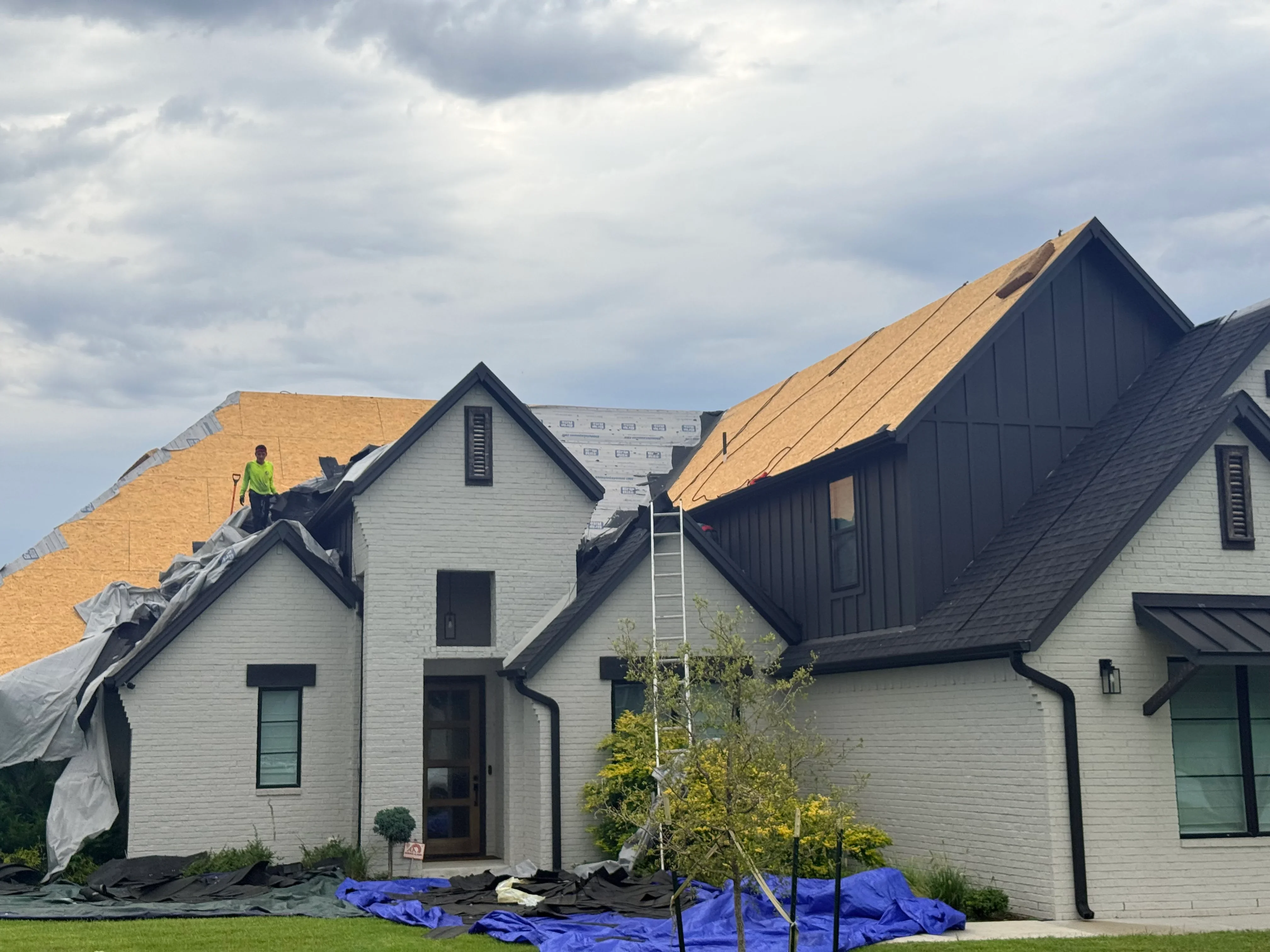 Residential roof replacement with new shingles and exposed underlayment on multi-slope farmhouse