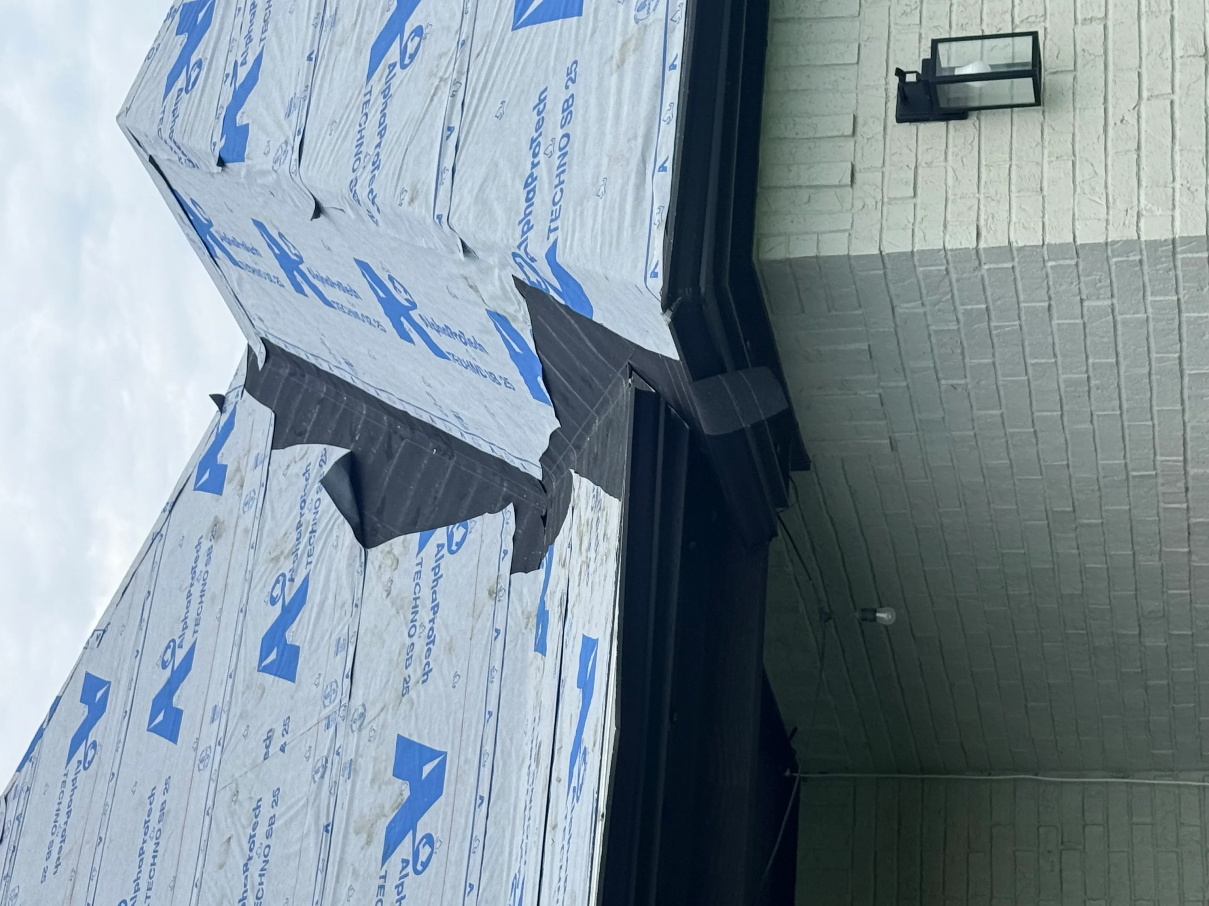 Synthetic roof underlayment with blue barrier and black drip edge flashing installed on roof sheathing
