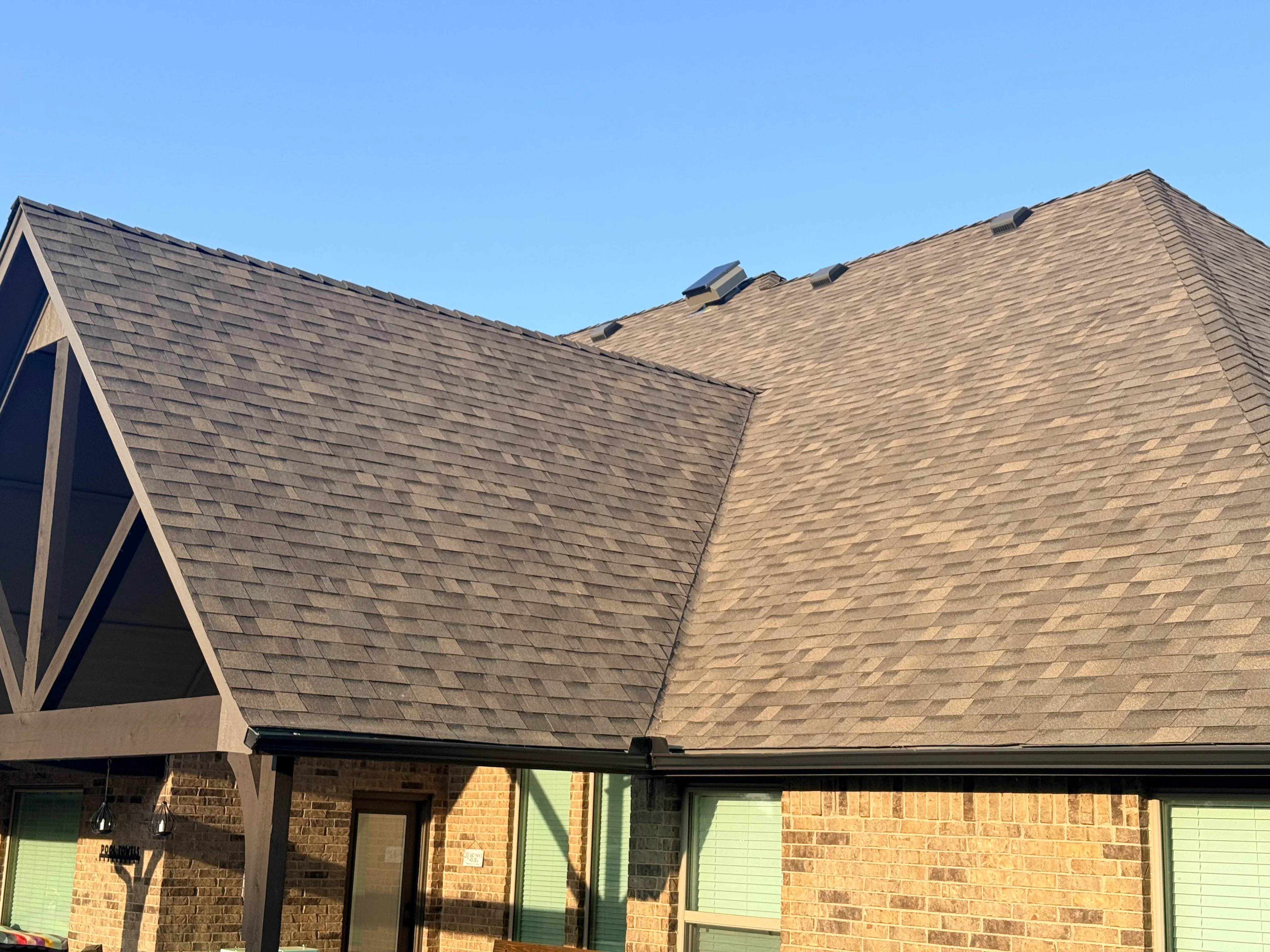 Architectural shingle roof with charcoal and tan shingles, ridge vents, brick home exterior