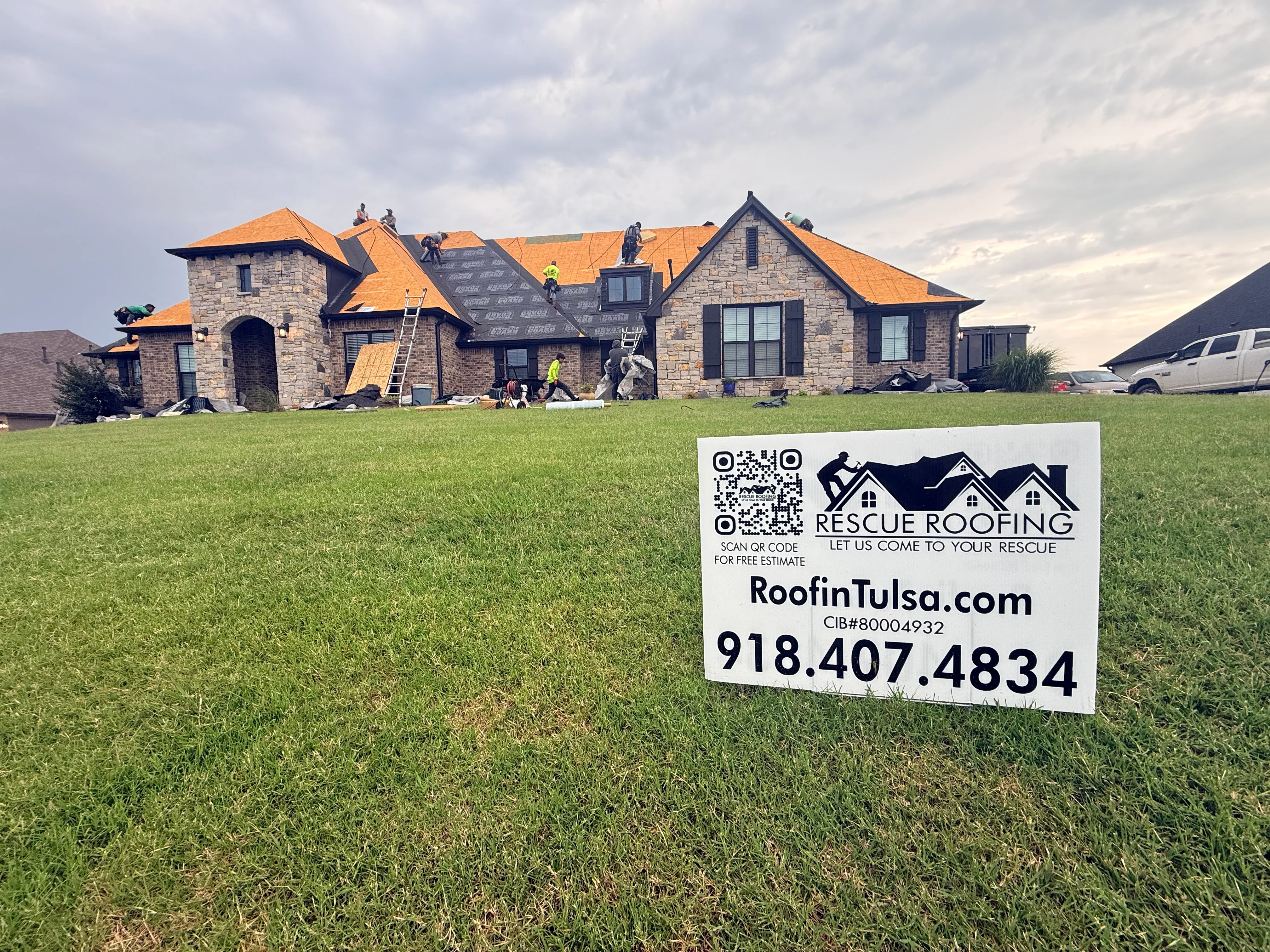 Residential roof replacement with orange architectural shingles on stone and brick home