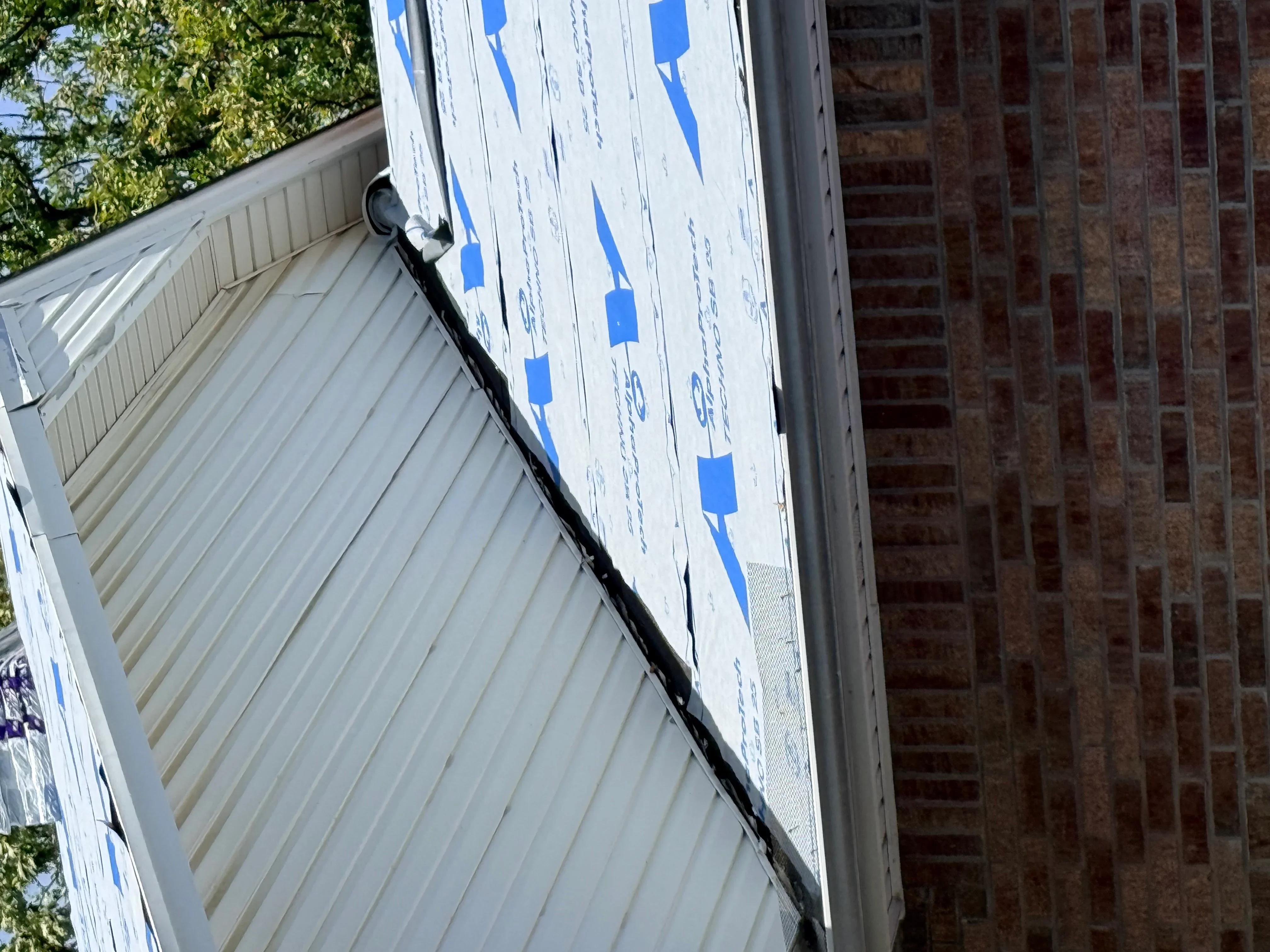 White corrugated metal roof panels with blue underlayment and black flashing detail