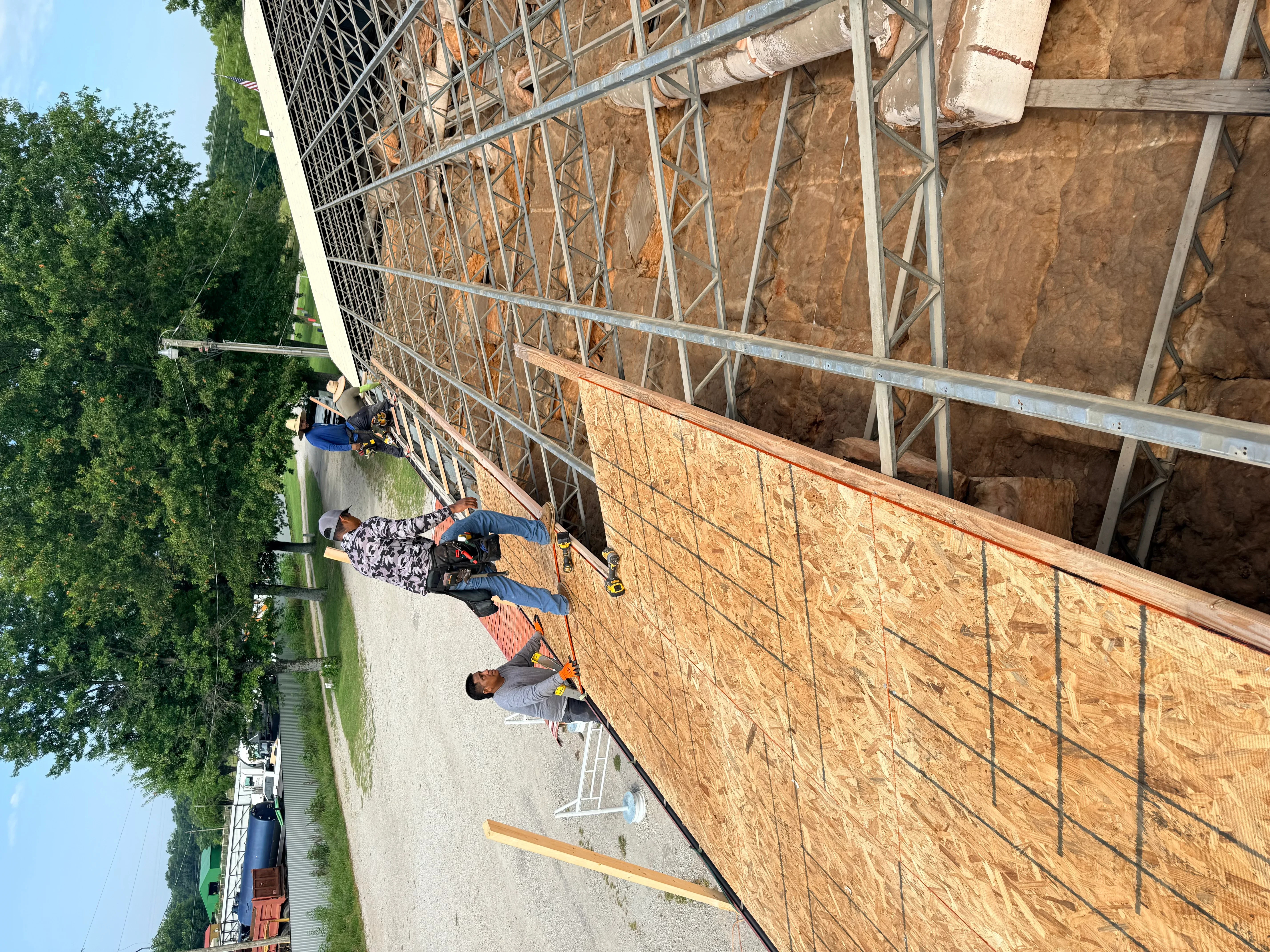 Roof framing with engineered trusses, metal bracing, and OSB sheathing installation