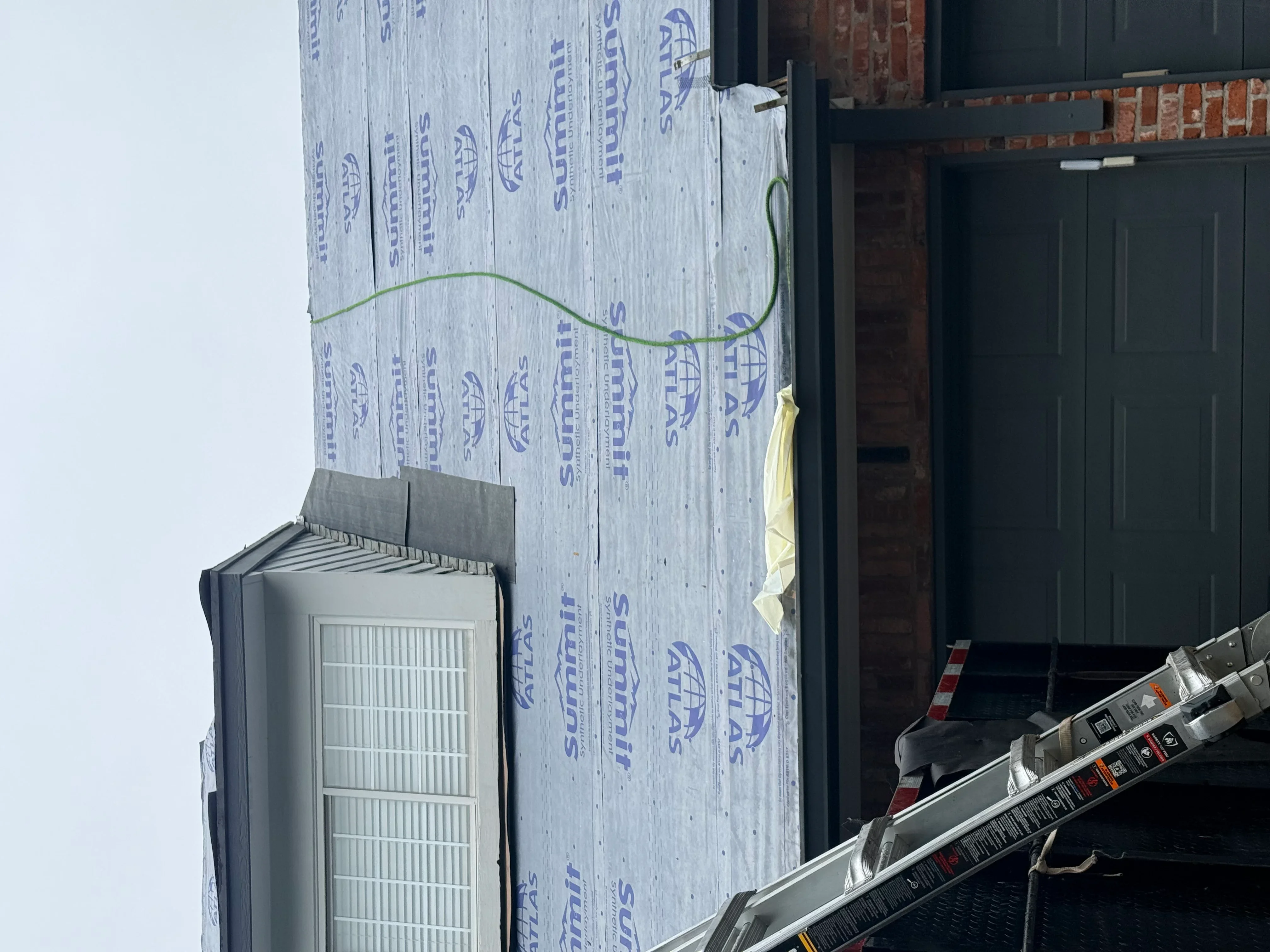 Roof sheathing with blue synthetic underlayment and green electrical conduit during installation