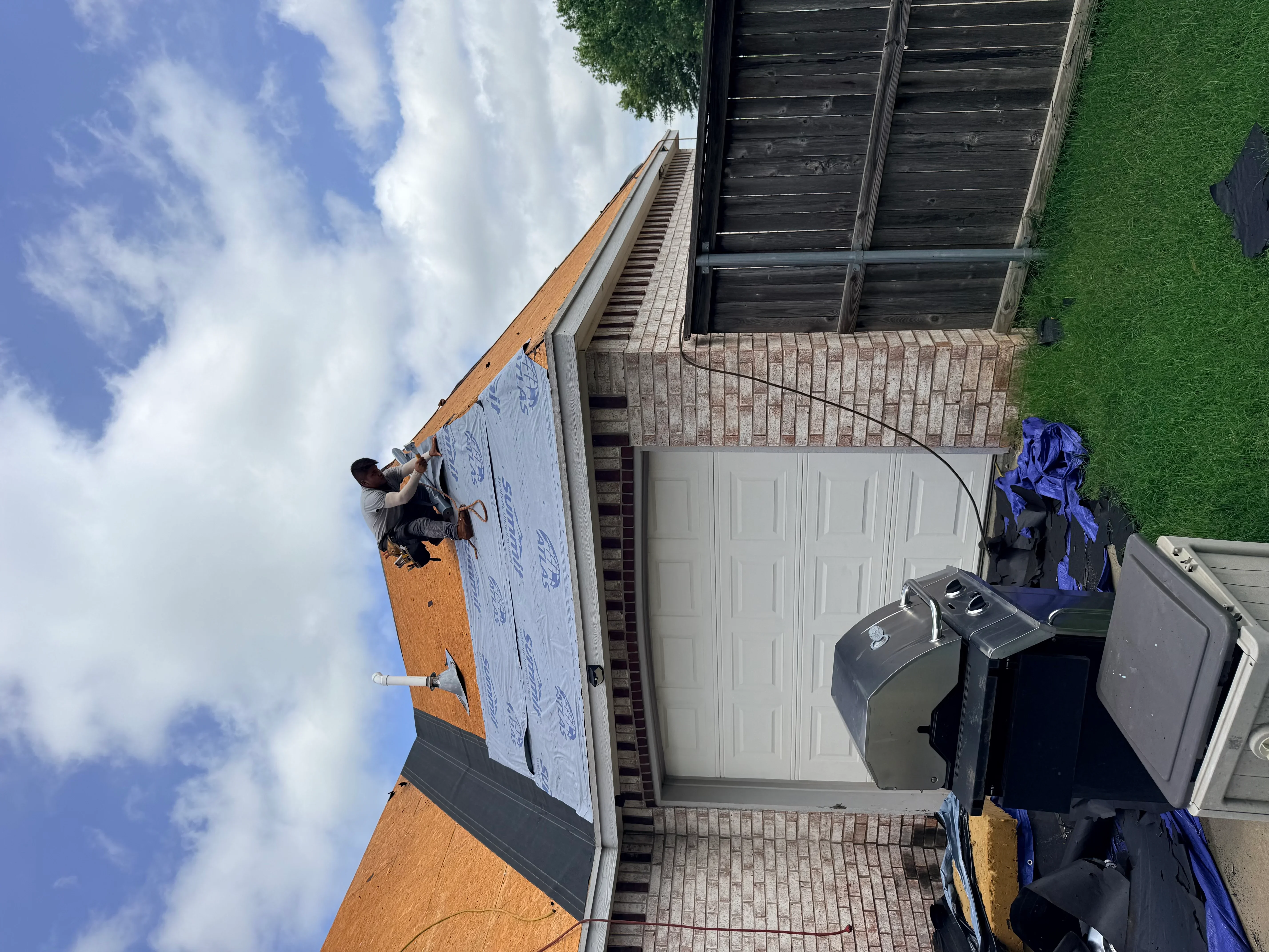 Roof sheathing with blue underlayment and protective barriers installed on residential home