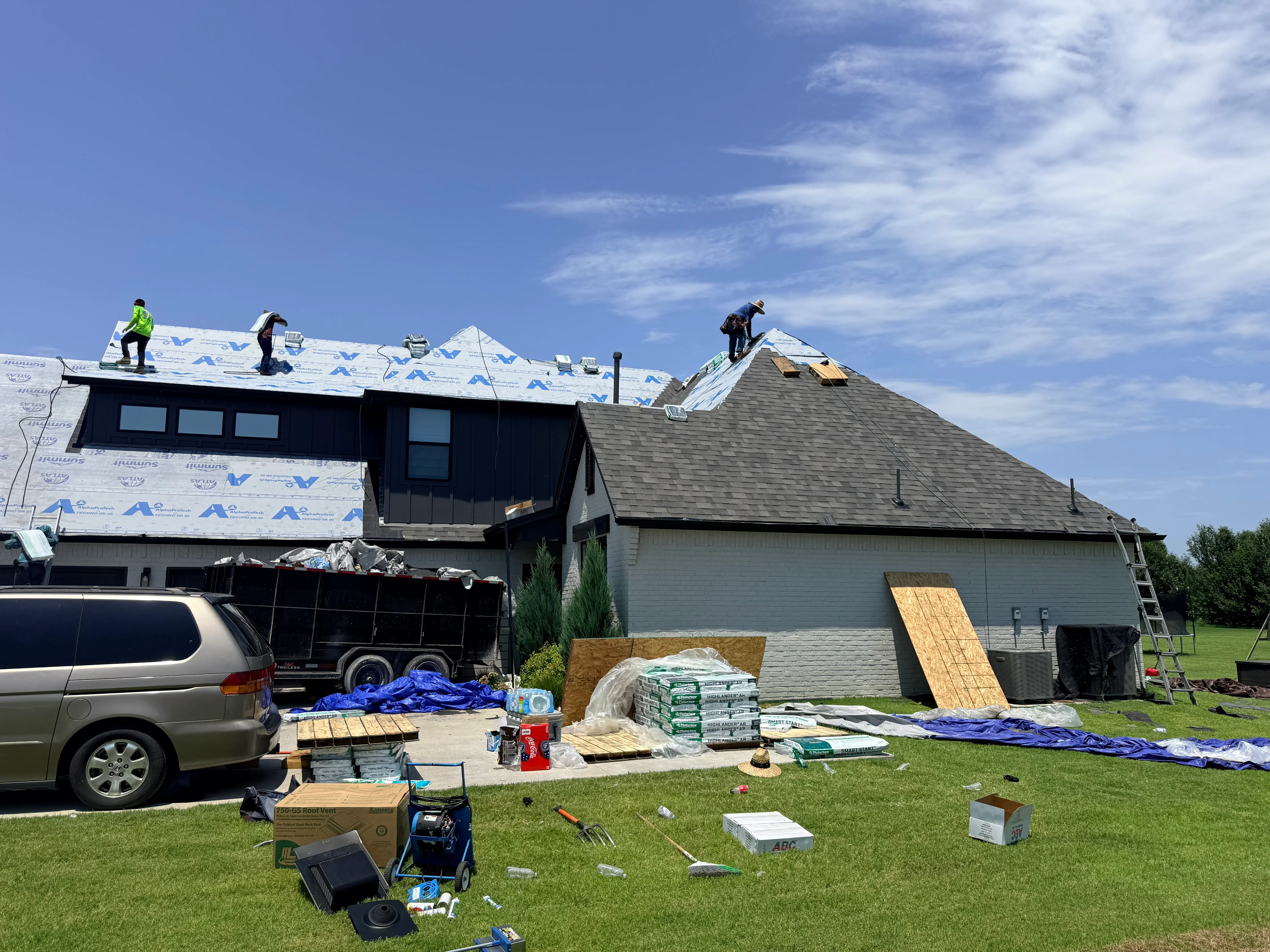 Roofers installing asphalt shingles with blue underlayment on residential home roof