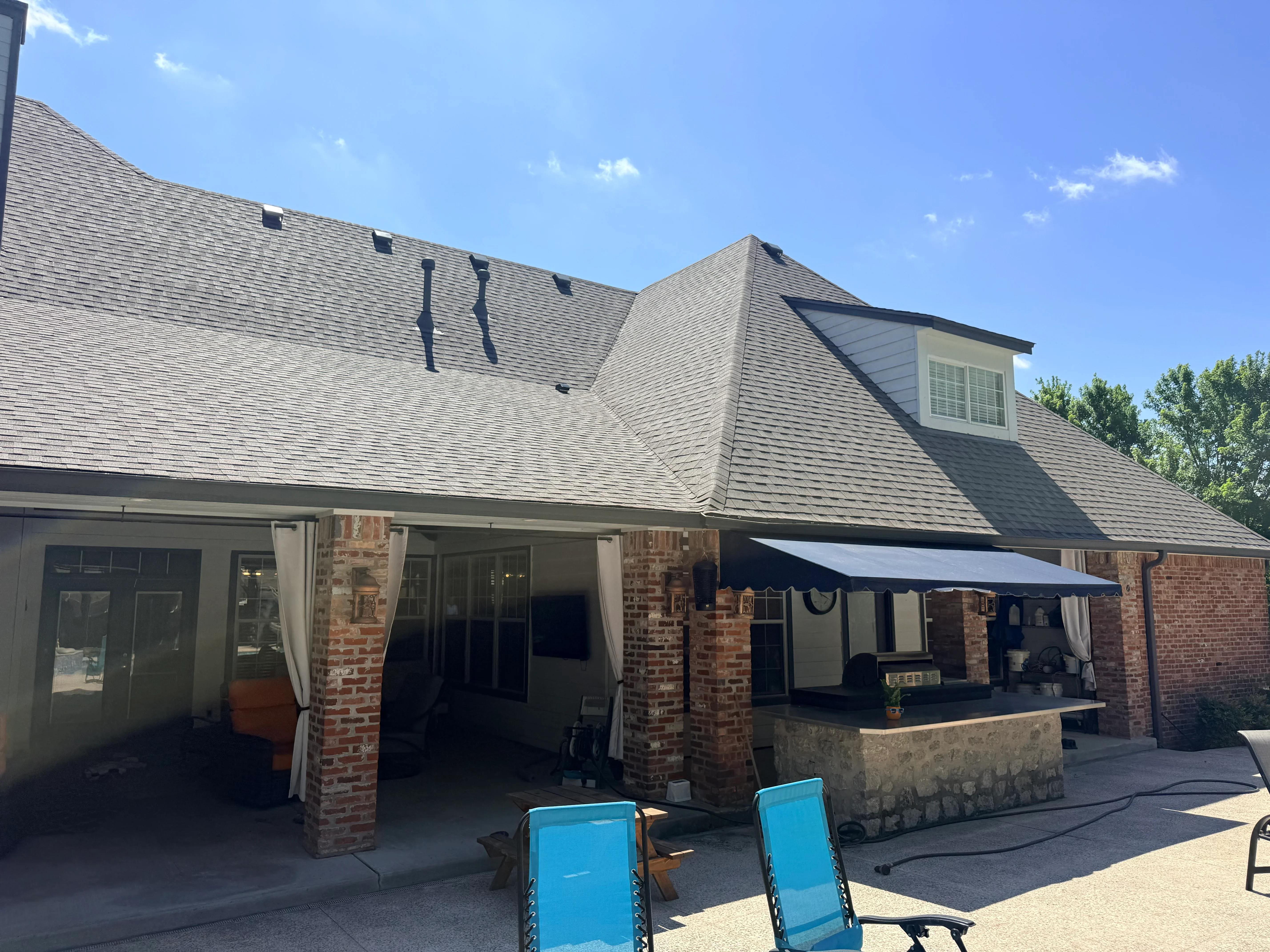 Gray architectural shingle roof with dormers, brick chimneys, and complex roofline on residential home