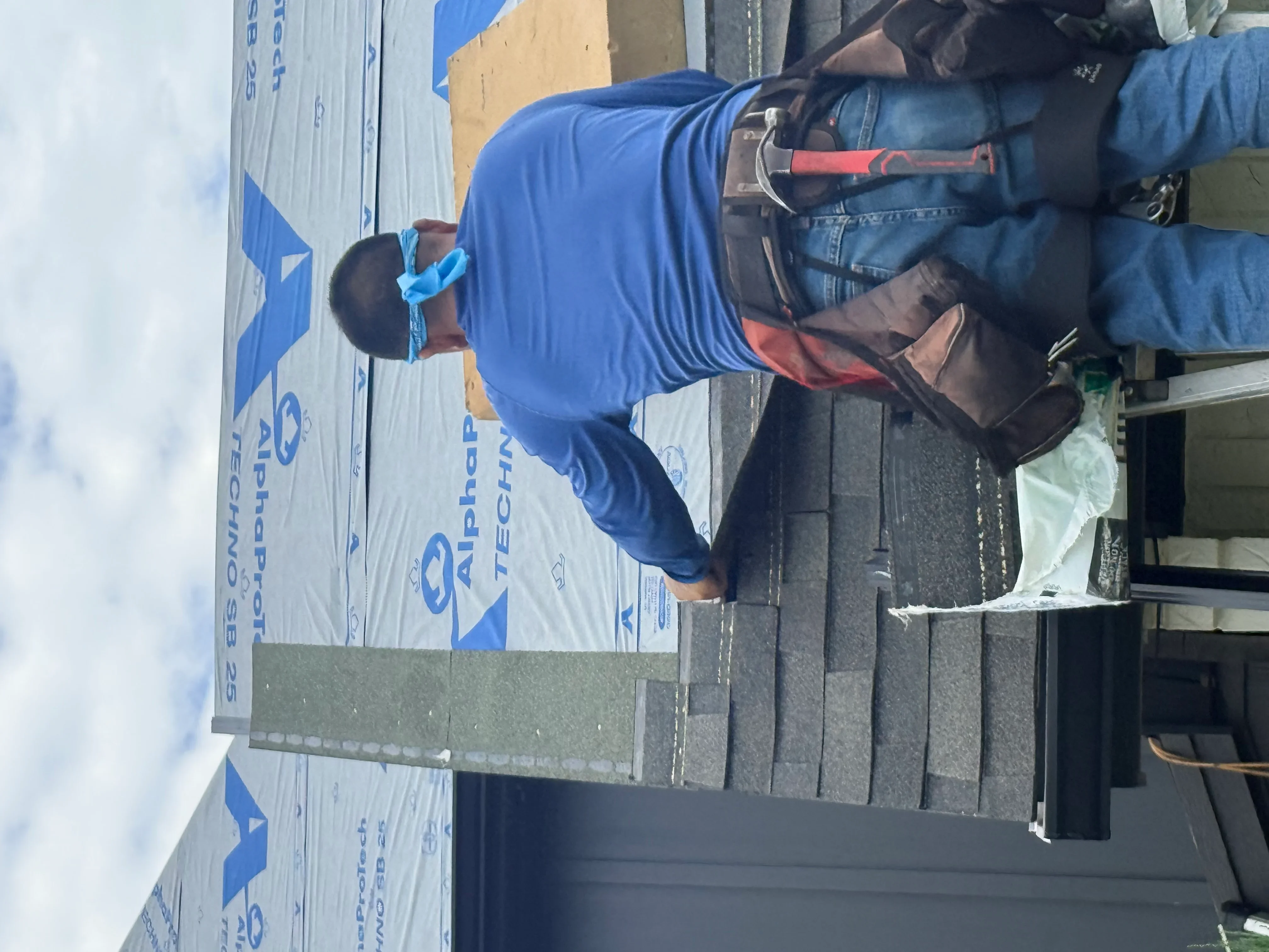 Roofer installing architectural shingles on residential roof with proper overlap and fastening