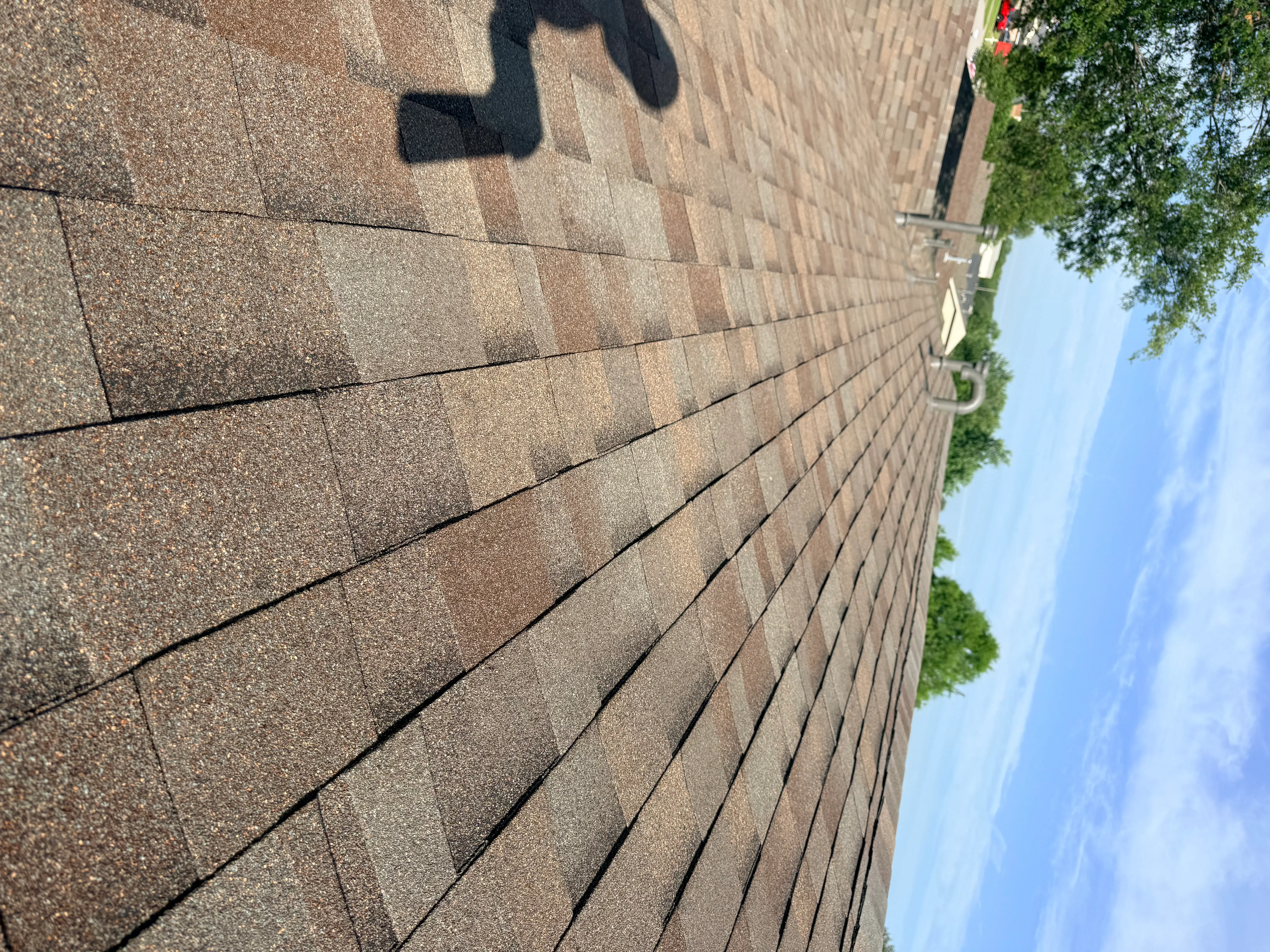 Newly installed architectural shingles in brown and tan tones with clean alignment and proper fastening