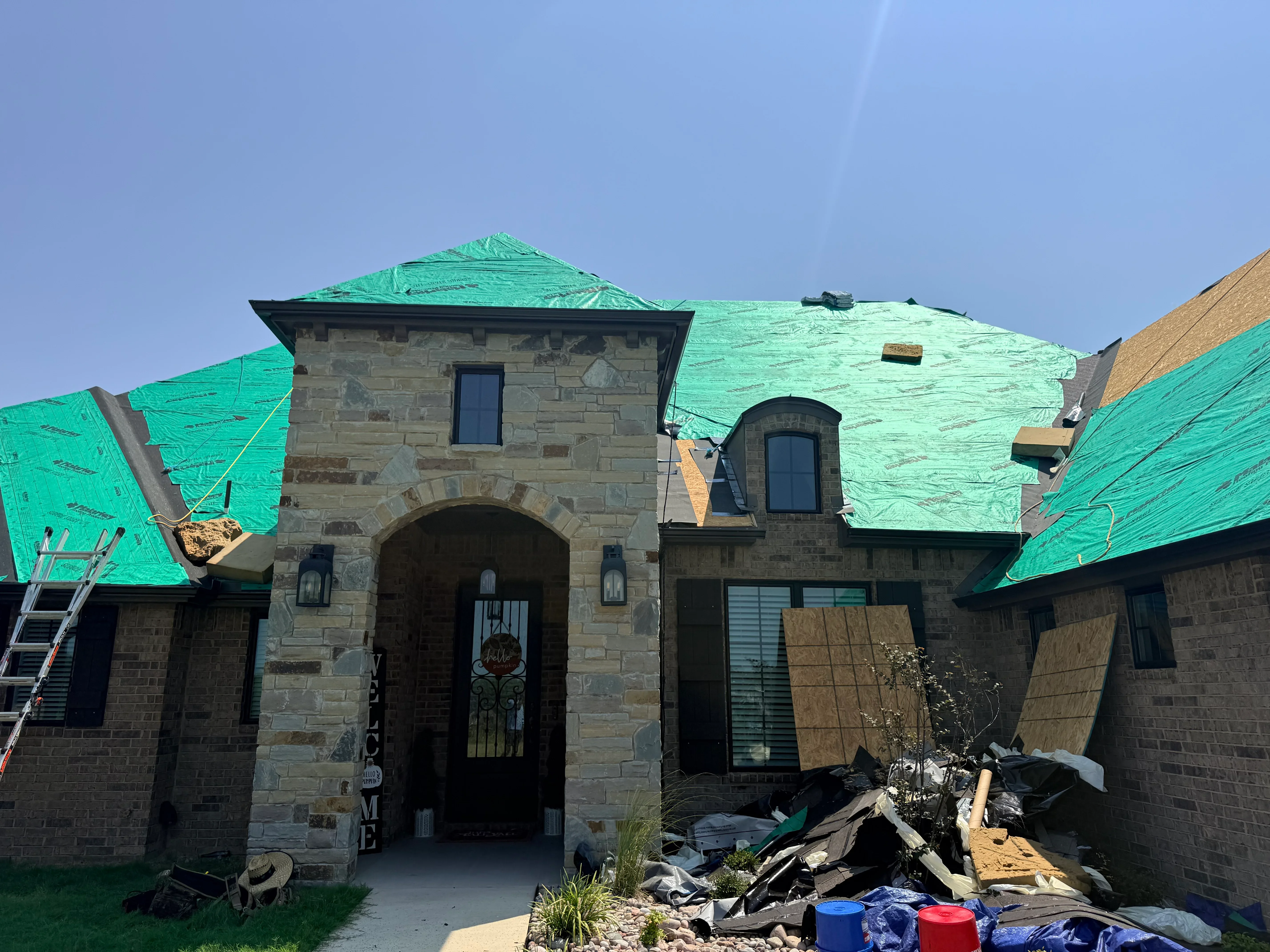 Stone mansion with green roofing underlayment installed on multiple roof sections and turret areas
