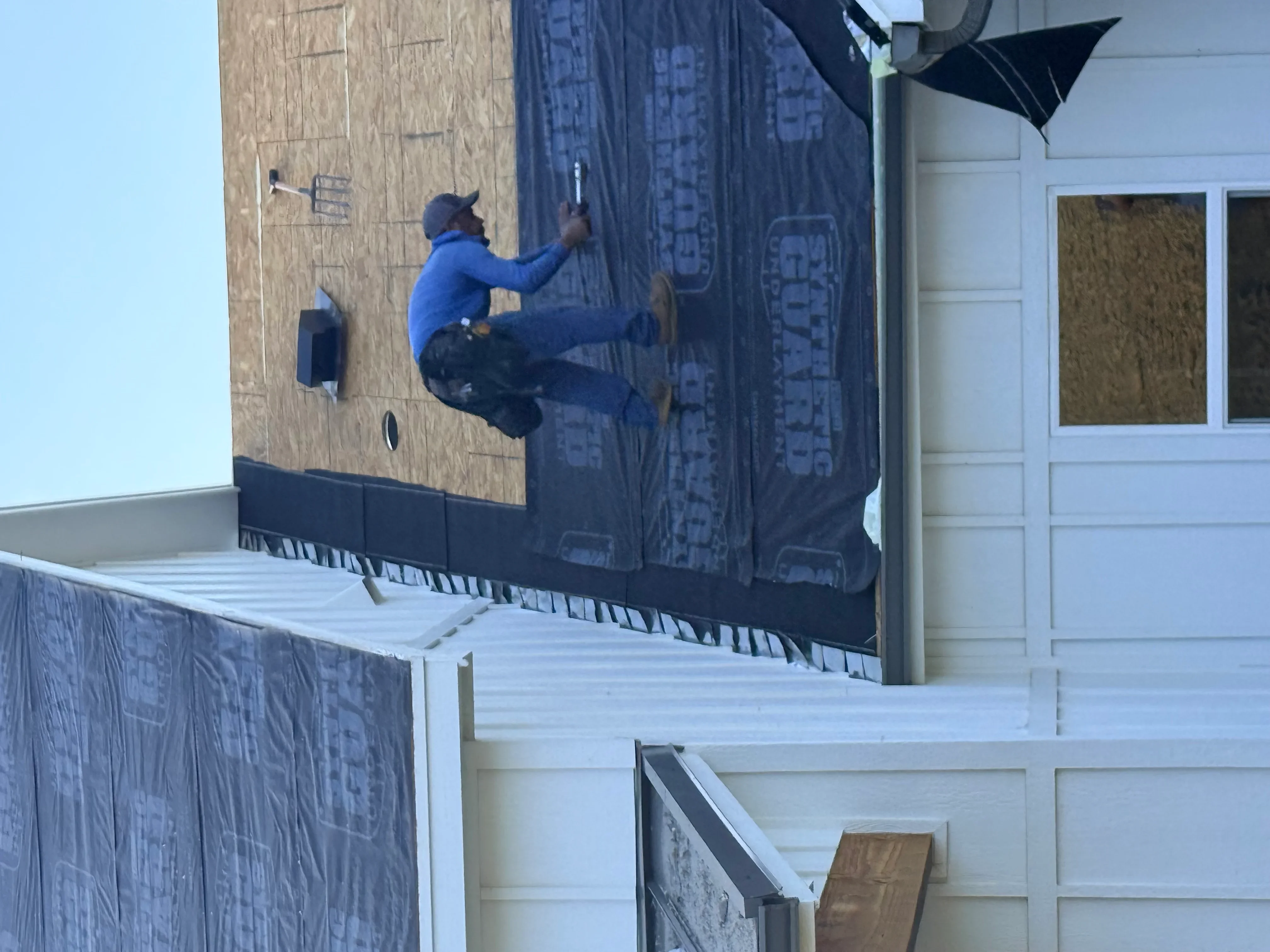 Worker installing fiber cement siding panels on residential exterior wall