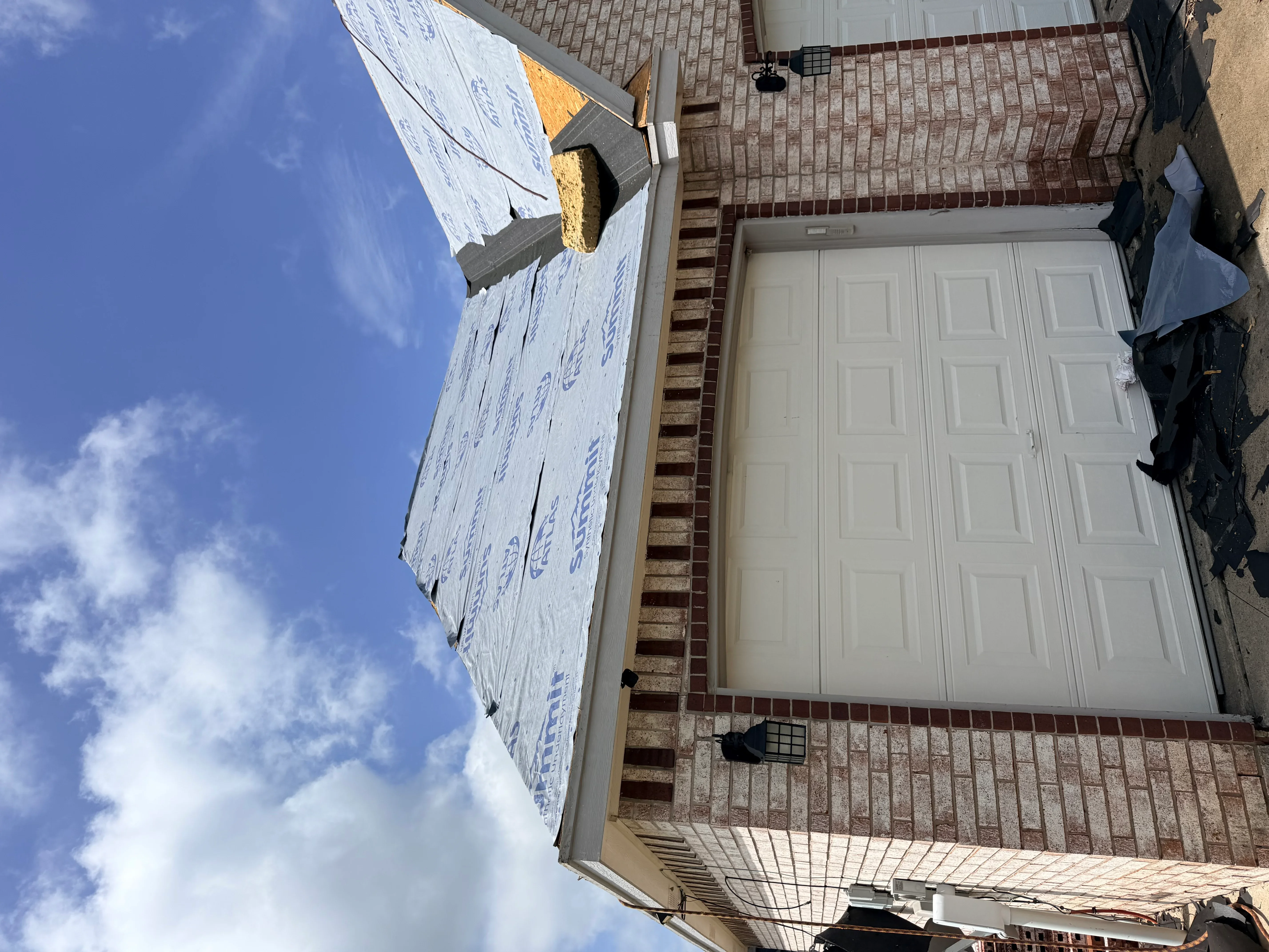New asphalt shingle roof with weather barrier on brick home, chimney flashing visible