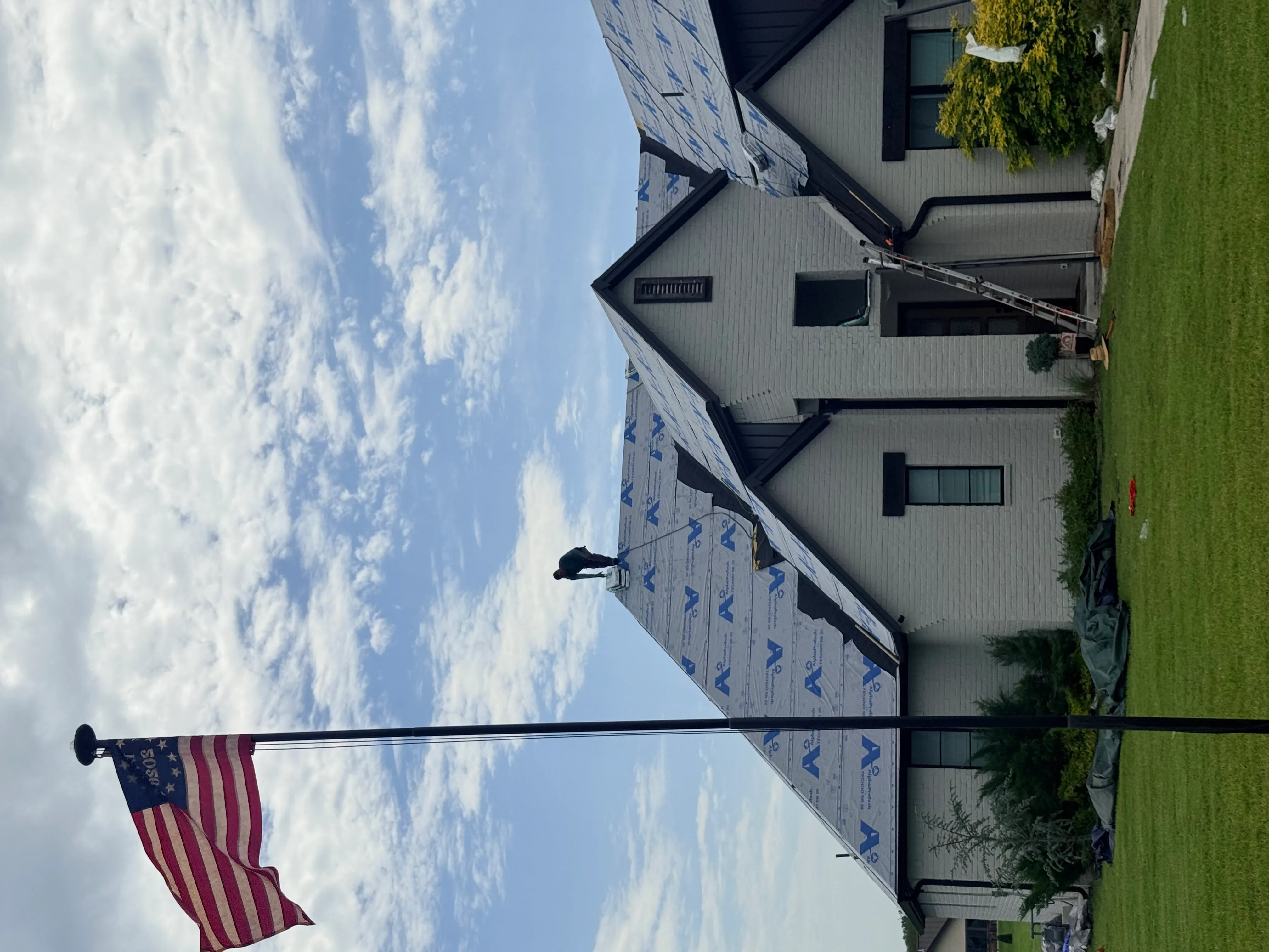 New roof installation with blue underlayment on residential home with multiple roof planes