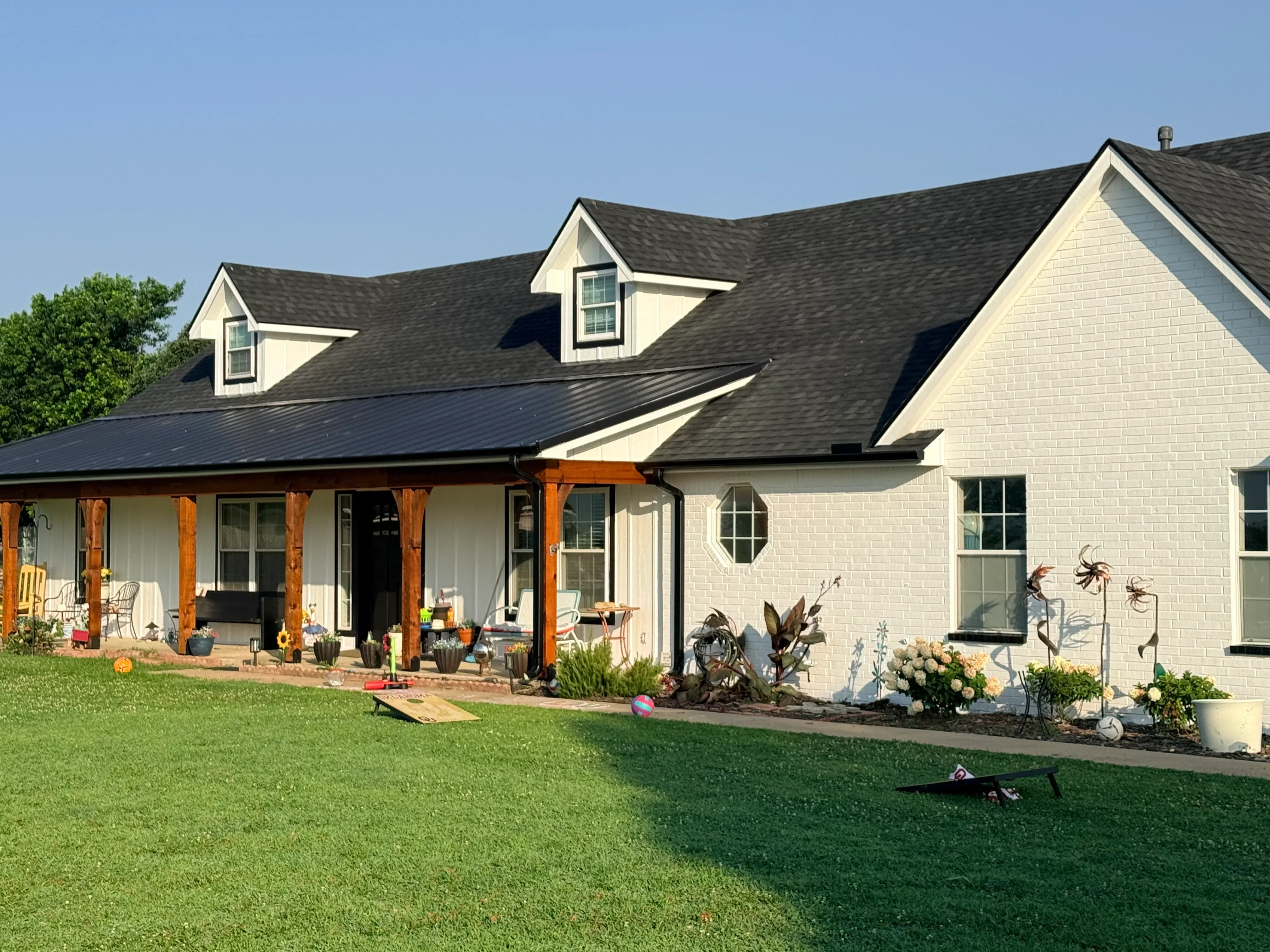 Charcoal gray architectural shingle roof with dormers on white brick home